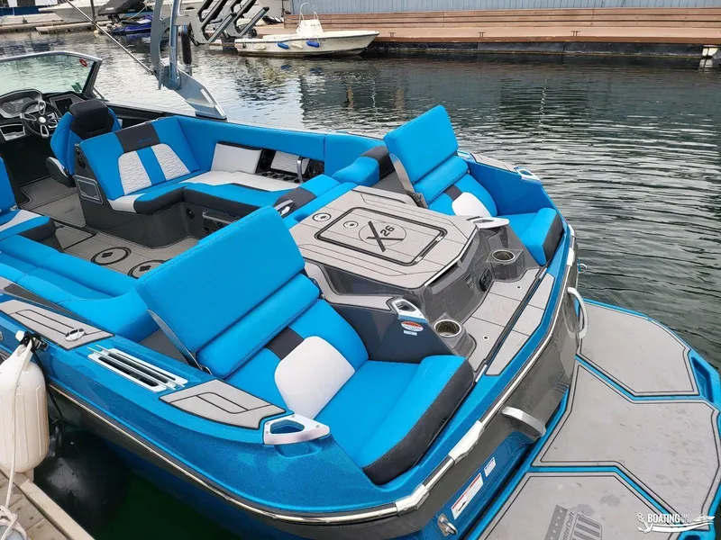 Slide: The Image of 2021 MasterCraft X26 boat with blue seating, docked at a marina. - 18
