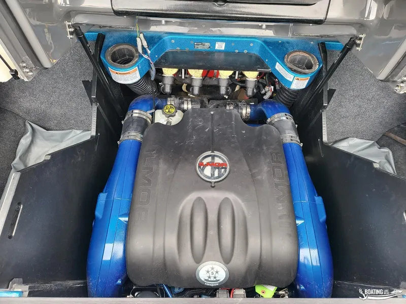 Slide: The Image of 2021 MasterCraft X26 engine compartment with Ilmor engine, featuring blue hoses and black cover. - 22