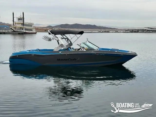Slide: The Image of 2021 MasterCraft X26 boat on calm lake with distant hills. - 4