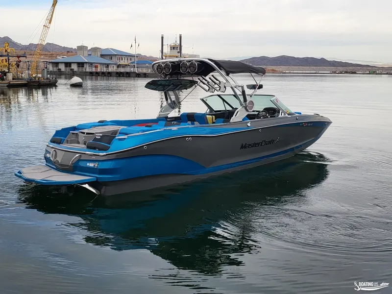 Slide: The Image of 2021 MasterCraft X26 boat on calm water, featuring sleek design and vibrant blue accents. - 7