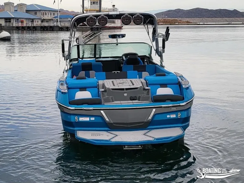 Slide: The Image of 2021 MasterCraft X26 boat in blue, docked on calm water. - 8
