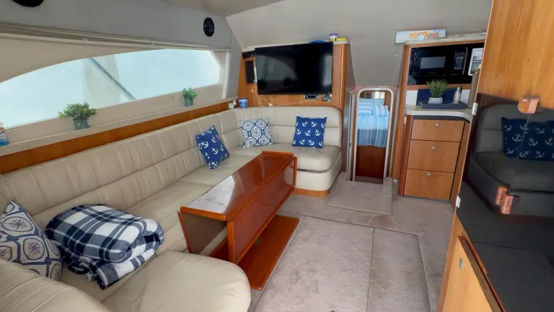 Slide: The Image of 1999 Luhrs 360 Convertible yacht interior with beige seating, wooden table, and modern amenities. - 12