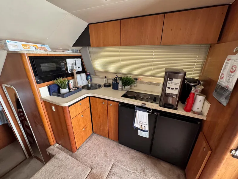Slide: The Image of 1999 Luhrs 360 Convertible yacht kitchen with wooden cabinets, appliances, and countertop decor. - 14