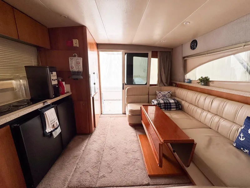 Slide: The Image of 1999 Luhrs 360 Convertible yacht interior with kitchen, seating area, and wooden table. - 15