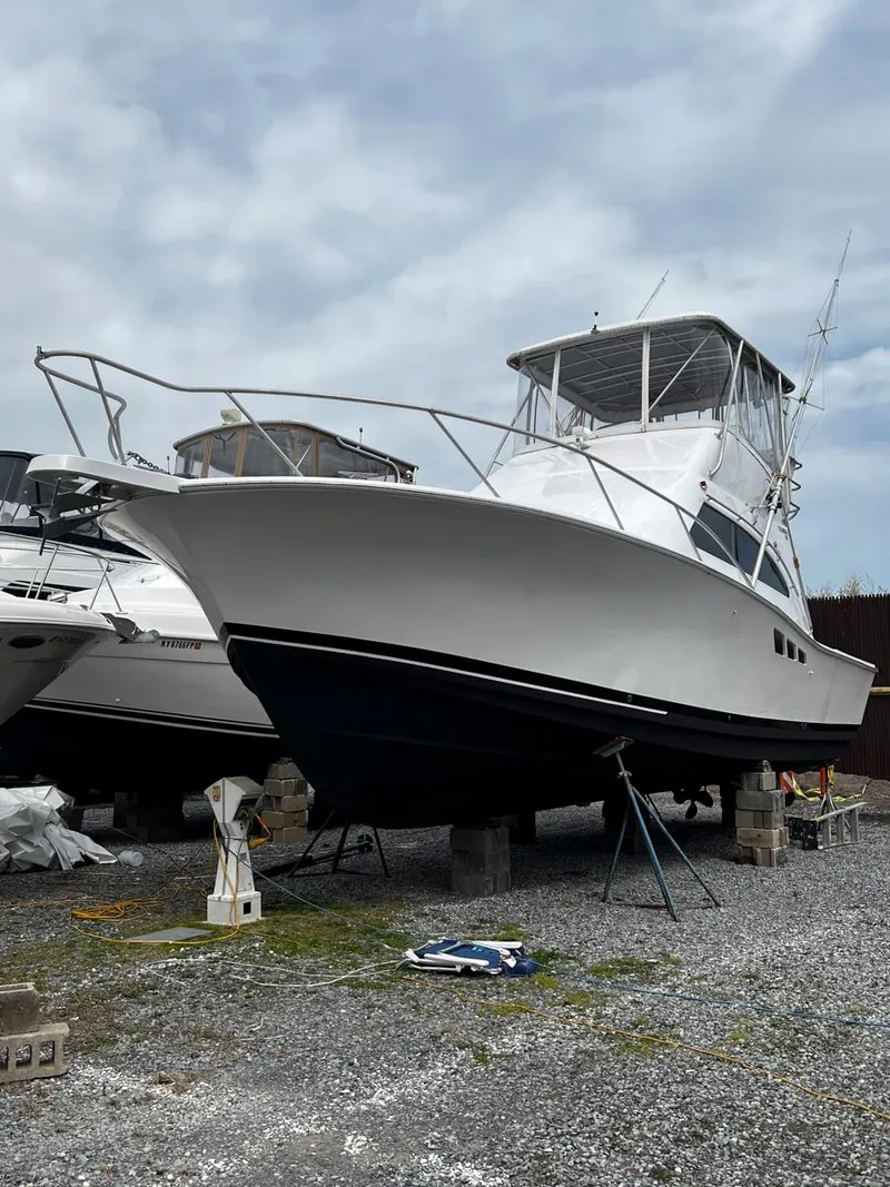 Slide: The Image of 1999 Luhrs 360 Convertible boat on dry dock, white hull, overcast sky. - 5