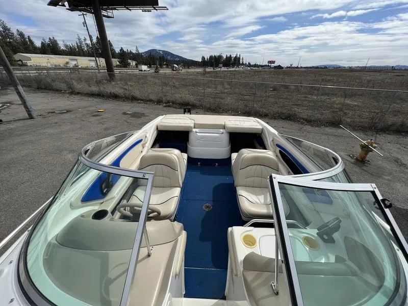 Slide: The Image of 1997 Sea Ray 210 Open Bow boat with beige seating and blue flooring, parked outdoors. - 11