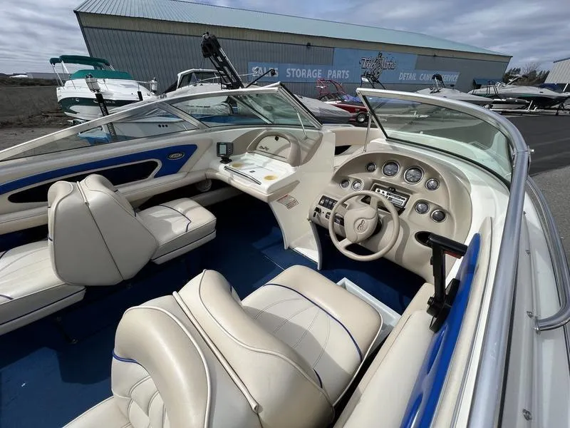 Slide: The Image of 1997 Sea Ray 210 Open Bow boat interior with beige seating and dashboard controls. - 7