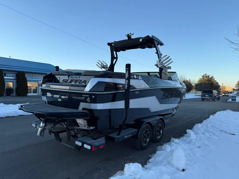 Slide: The Image of 2022 Supra SL boat on trailer in snowy parking lot, rear view. - 8