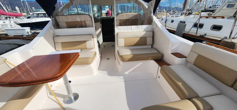 Slide: The Image of 2012 Tiara Yachts 3100 Coronet interior with beige seating and wooden table, docked at marina. - 20