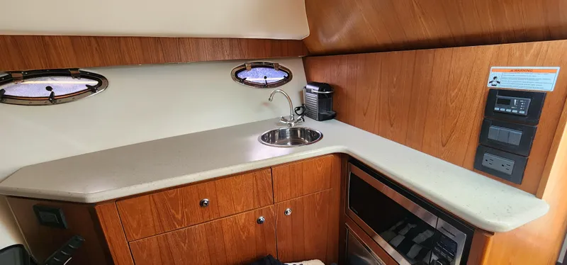 Slide: The Image of 2012 Tiara Yachts 3100 Coronet interior with kitchenette, sink, and wooden cabinetry. - 24