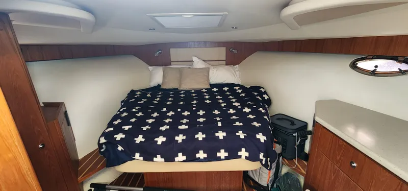 Slide: The Image of 2012 Tiara Yachts 3100 Coronet cabin with bed, wood accents, and storage. - 27