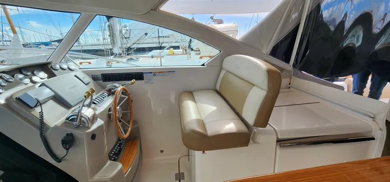 Slide: The Image of 2012 Tiara Yachts 3100 Coronet helm with beige seating and wooden steering wheel. - 7
