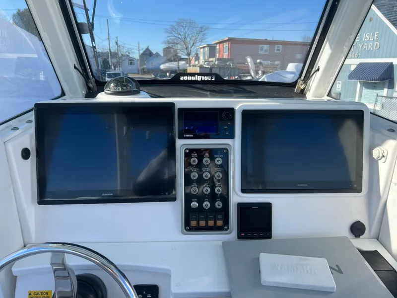 Slide: The Image of 2014 Everglades 325 Center Console boat on calm water, surrounded by lush greenery. - 8