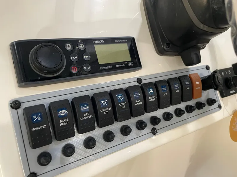 Slide: The Image of Control panel of 2023 Key West 239 DFS boat with various switches and a Fusion stereo. - 25