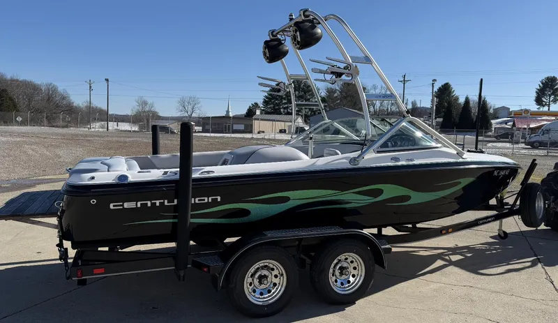 Slide: The Image of 2007 Centurion T5 boat on trailer, black with green accents, parked outdoors on a sunny day. - 1