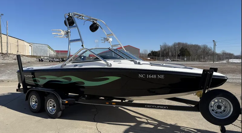 Slide: The Image of 2007 Centurion T5 boat on trailer with green flame design, parked outdoors. - 2