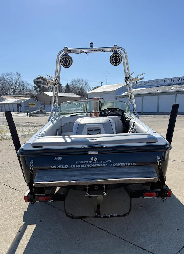 Slide: The Image of 2007 Centurion T5 boat, rear view, showcasing wakeboard tower and seating, parked outdoors. - 3