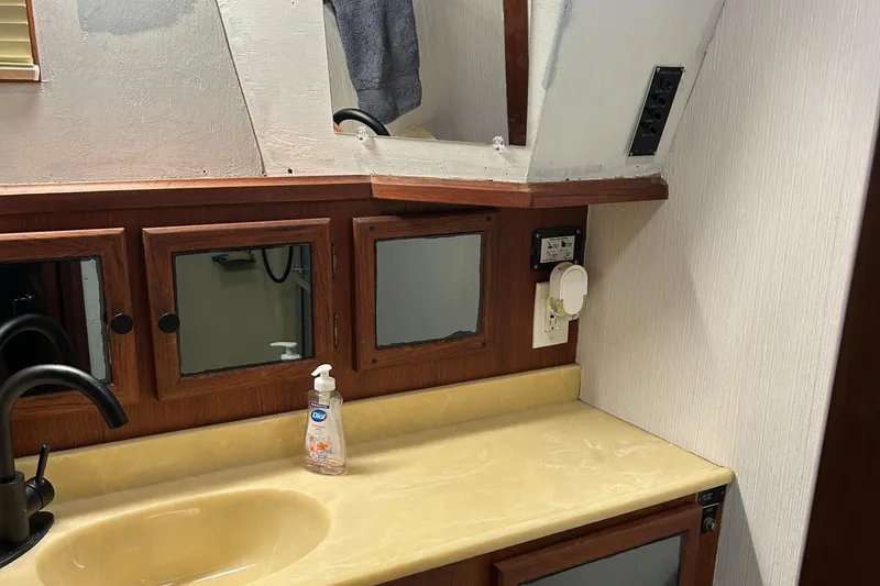 Slide: The Image of 1985 Viking 50 Cockpit MY bathroom with wooden cabinets and beige countertop. - 28