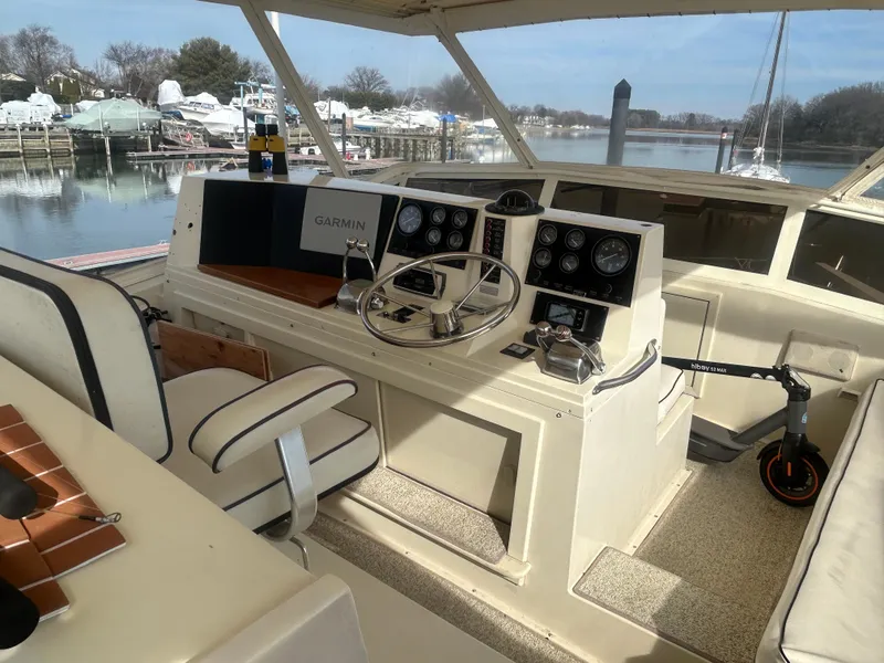 Slide: The Image of 1985 Viking 50 Cockpit MY helm with Garmin navigation, docked by a serene waterfront. - 35