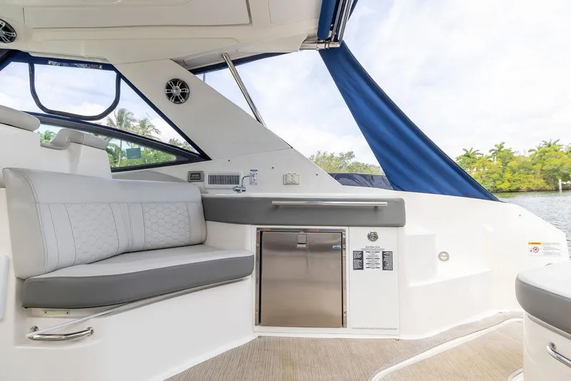 Slide: The Image of 2020 Sea Ray Sundancer 320 interior with seating and kitchenette, featuring blue canopy and scenic view. - 14