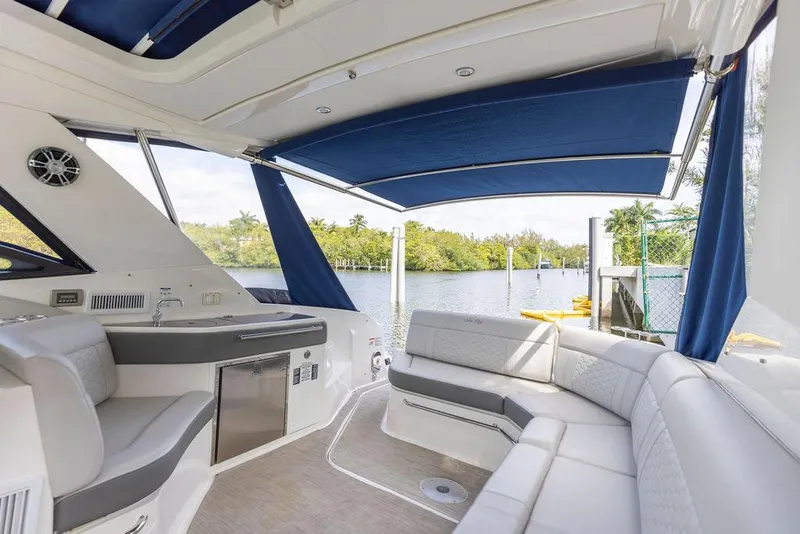 Slide: The Image of 2020 Sea Ray Sundancer 320 interior with blue canopy and waterfront view. - 15
