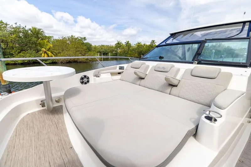 Slide: The Image of 2020 Sea Ray Sundancer 320 deck with seating and table, surrounded by lush greenery. - 37