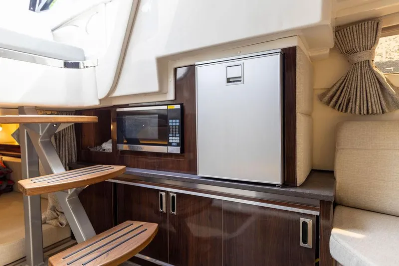Slide: The Image of Interior of 2020 Sea Ray Sundancer 320 with microwave, fridge, and wooden cabinetry. - 40