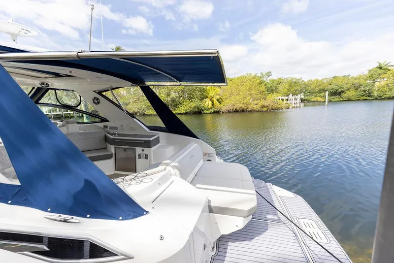 Slide: The Image of 2020 Sea Ray Sundancer 320 yacht with blue canopy on a serene waterway. - 6