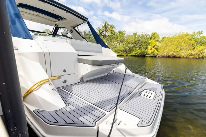 Slide: The Image of 2020 Sea Ray Sundancer 320 yacht with spacious deck, docked near lush greenery and calm waters. - 7