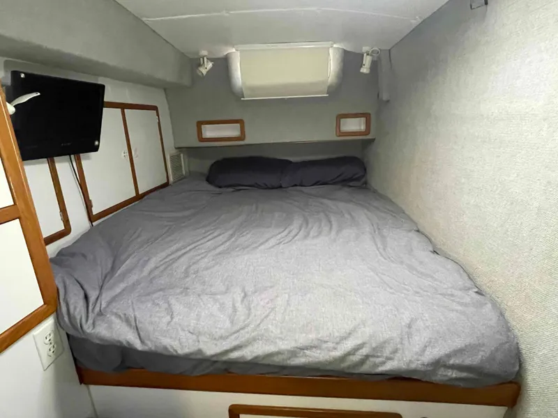Slide: The Image of Cozy bedroom in 2000 Manta 42 Catamaran with gray bedding and small TV. - 10