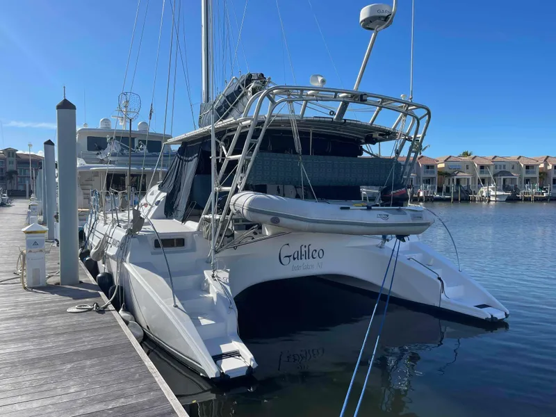 Slide: The Image of 2000 Manta 42 Catamaran docked at marina, clear blue sky, calm water. - 2