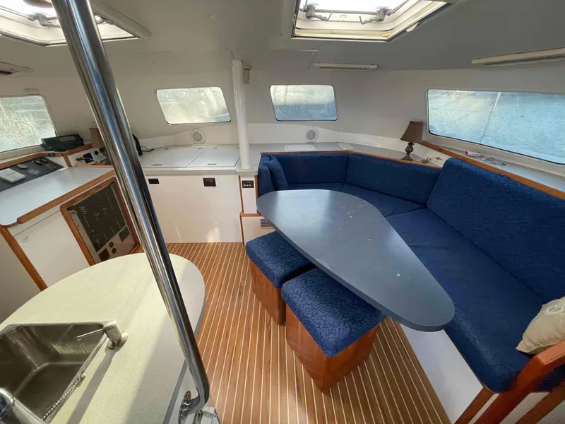 Slide: The Image of Interior of 2000 Manta 42 Catamaran with blue seating and wooden flooring. - 3