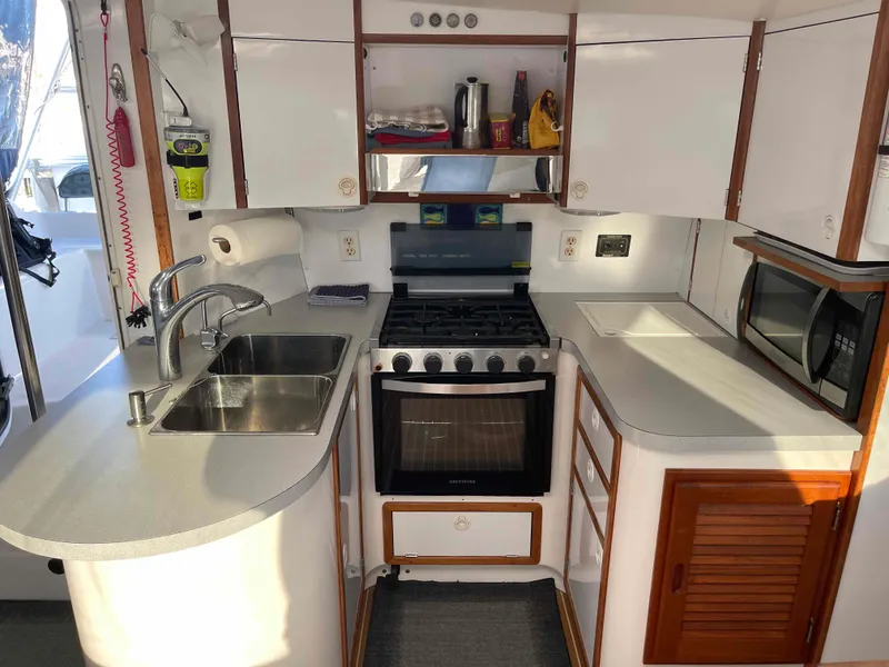 Slide: The Image of Compact kitchen in a 2000 Manta 42 Catamaran with stove, sink, and microwave. - 5