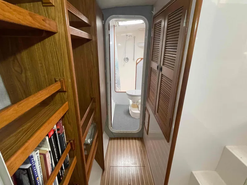 Slide: The Image of Interior of 2000 Manta 42 Catamaran, featuring wooden shelves, closet, and visible bathroom. - 7