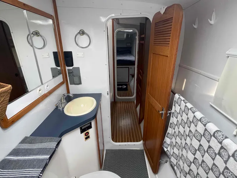 Slide: The Image of Bathroom interior of 2000 Manta 42 Catamaran with sink, mirror, and wooden door. - 9