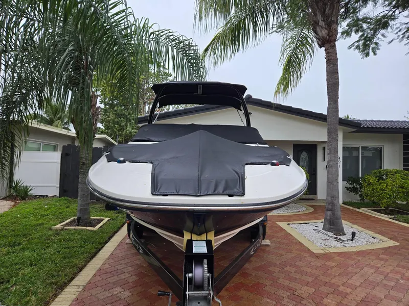 Slide: The Image of 2015 Sea Ray 220 Sundeck boat on trailer, parked in a driveway with palm trees. - 10
