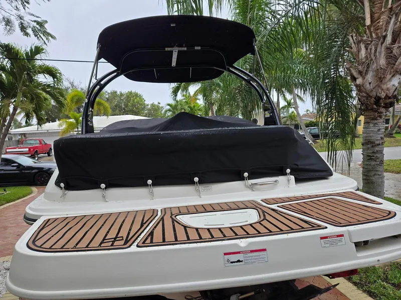 Slide: The Image of 2015 Sea Ray 220 Sundeck boat with covered deck, parked near palm trees. - 13