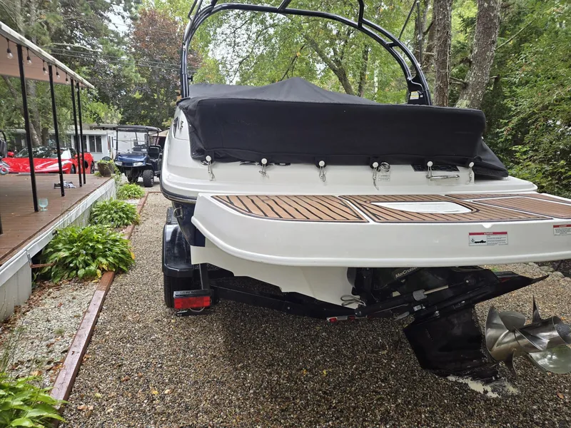 Slide: The Image of 2015 Sea Ray 220 Sundeck boat, rear view, parked on gravel with trees in background. - 20