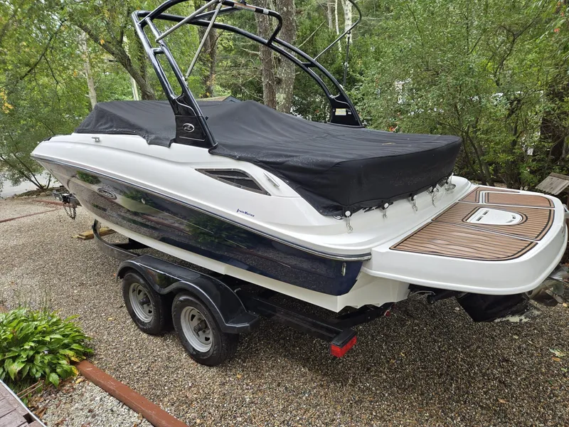 Slide: The Image of 2015 Sea Ray 220 Sundeck boat on trailer, covered, in a wooded area. - 3