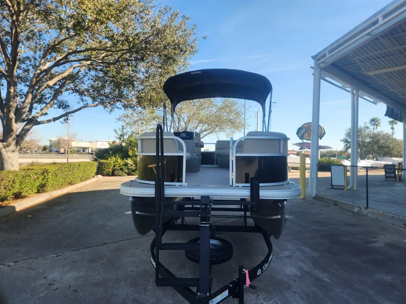 Slide: The Image of 2025 Sun Tracker Party Barge 16 DLX pontoon boat on trailer, parked outdoors. - 2