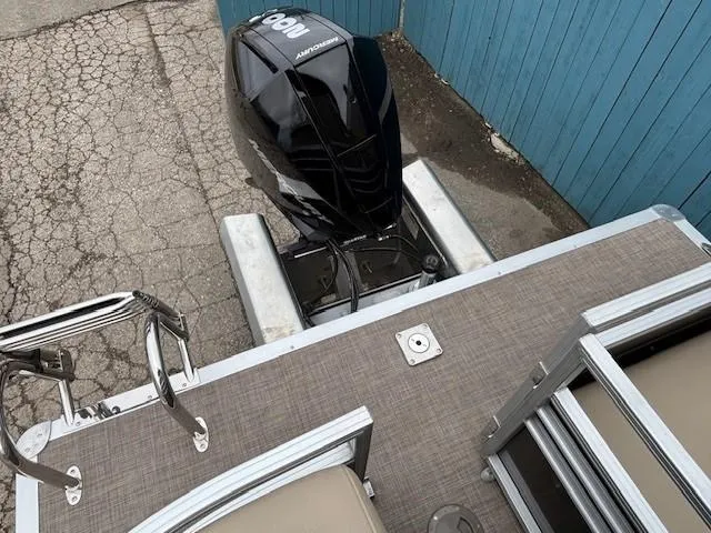 Slide: The Image of 2023 Sun Tracker Party Barge 22 RF XP3 with powerful outboard motor, docked by blue fence. - 29