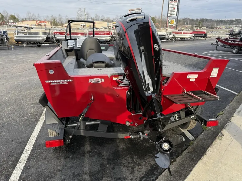 Slide: The Image of 2025 Tracker Pro Guide V-175 WT boat, red, rear view with motor, parked outdoors. - 4