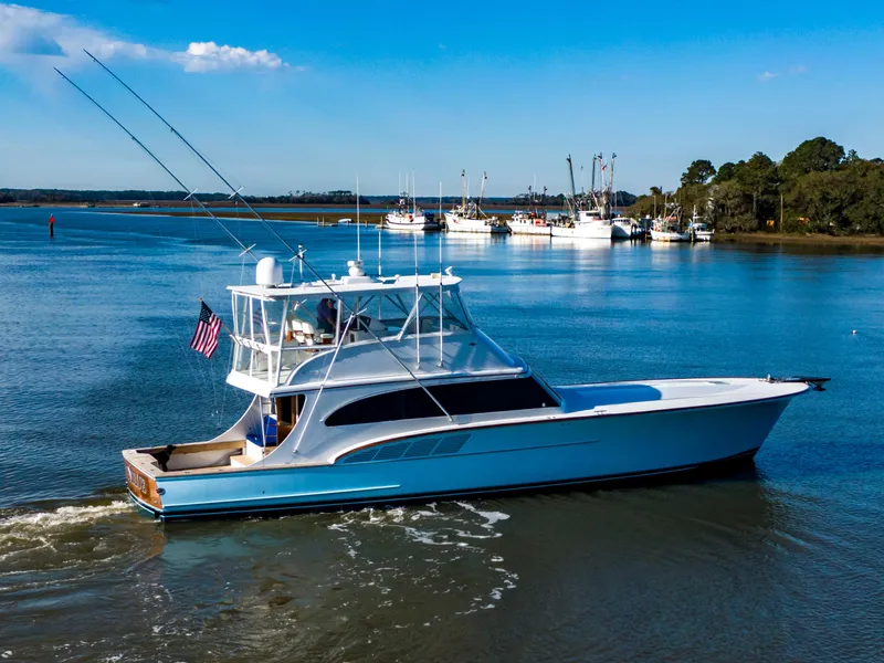 Slide: The Image of Custom Carolina 66 yacht, 2005 model, cruising on a serene waterway under a clear blue sky. - 15
