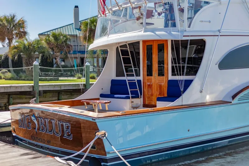 Slide: The Image of 2005 Custom Carolina 66 yacht docked, featuring wooden accents and blue seating. - 17