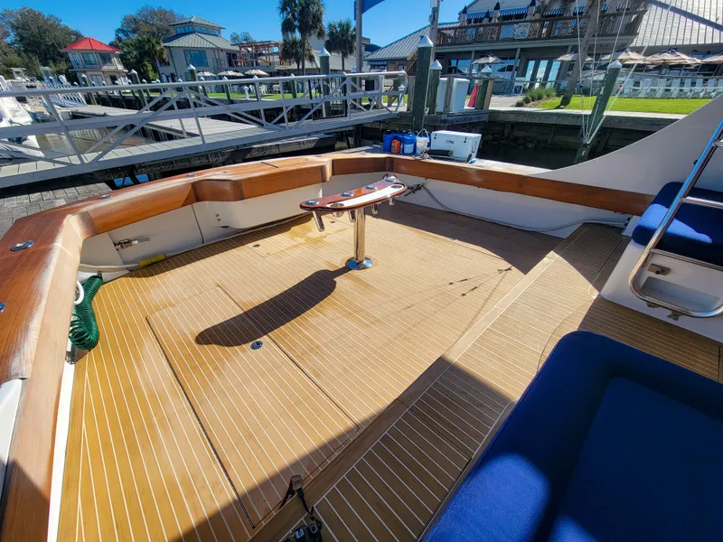 Slide: The Image of 2005 Custom Carolina 66 boat deck with wooden flooring and seating at a marina. - 20