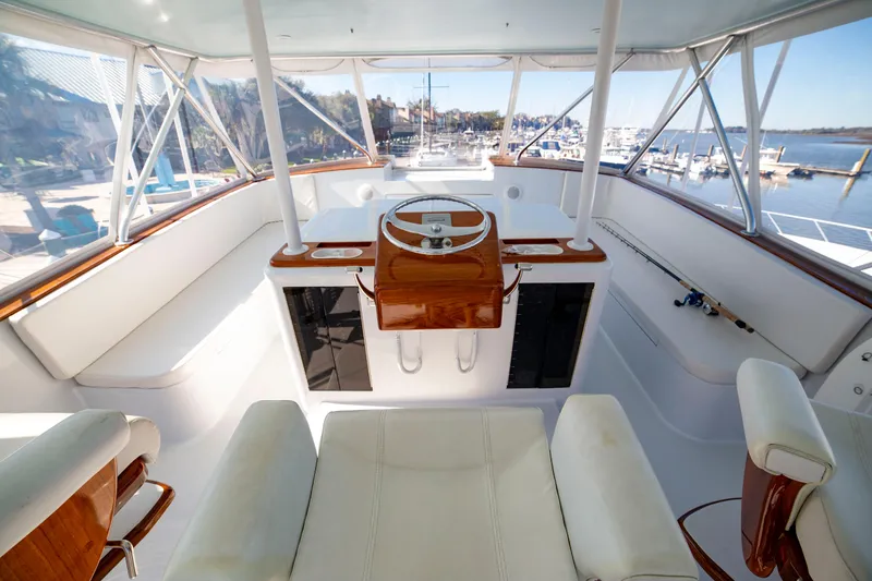 Slide: The Image of Cockpit view of 2005 Custom Carolina 66 yacht, featuring elegant wood accents and marina backdrop. - 40