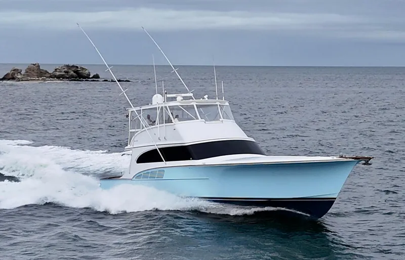 Slide: The Image of Custom Carolina 66 yacht cruising on the ocean, 2005 model, with rocky island in background. - 49