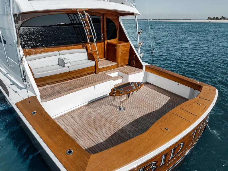 Slide: The Image of 2023 Viking 72 Convertible yacht with spacious teak deck and seating, cruising on clear blue water. - 19