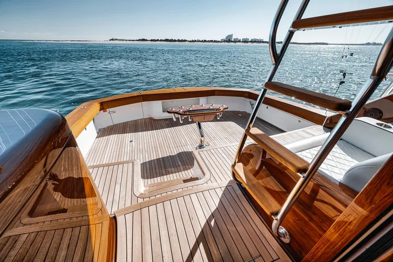 Slide: The Image of 2023 Viking 72 Convertible yacht deck with wooden finish, overlooking serene ocean waters. - 20