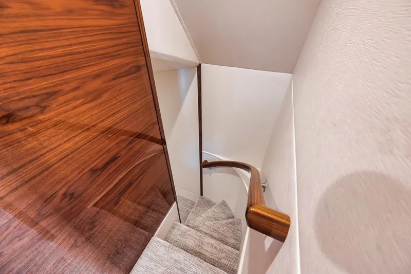 Slide: The Image of Staircase inside 2023 Viking 72 Convertible yacht with wooden paneling and sleek design. - 39